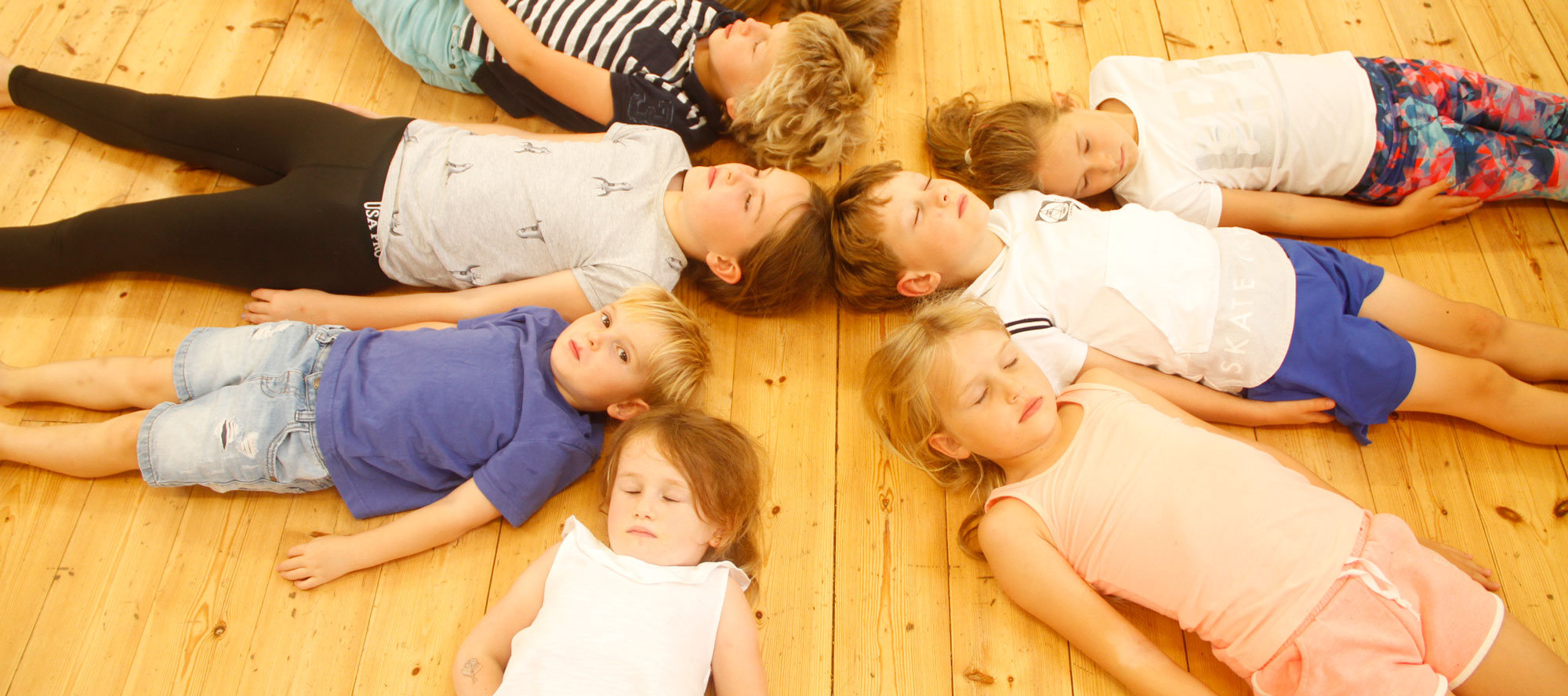 Year 2 pupils resting in a circle on the school hall floor