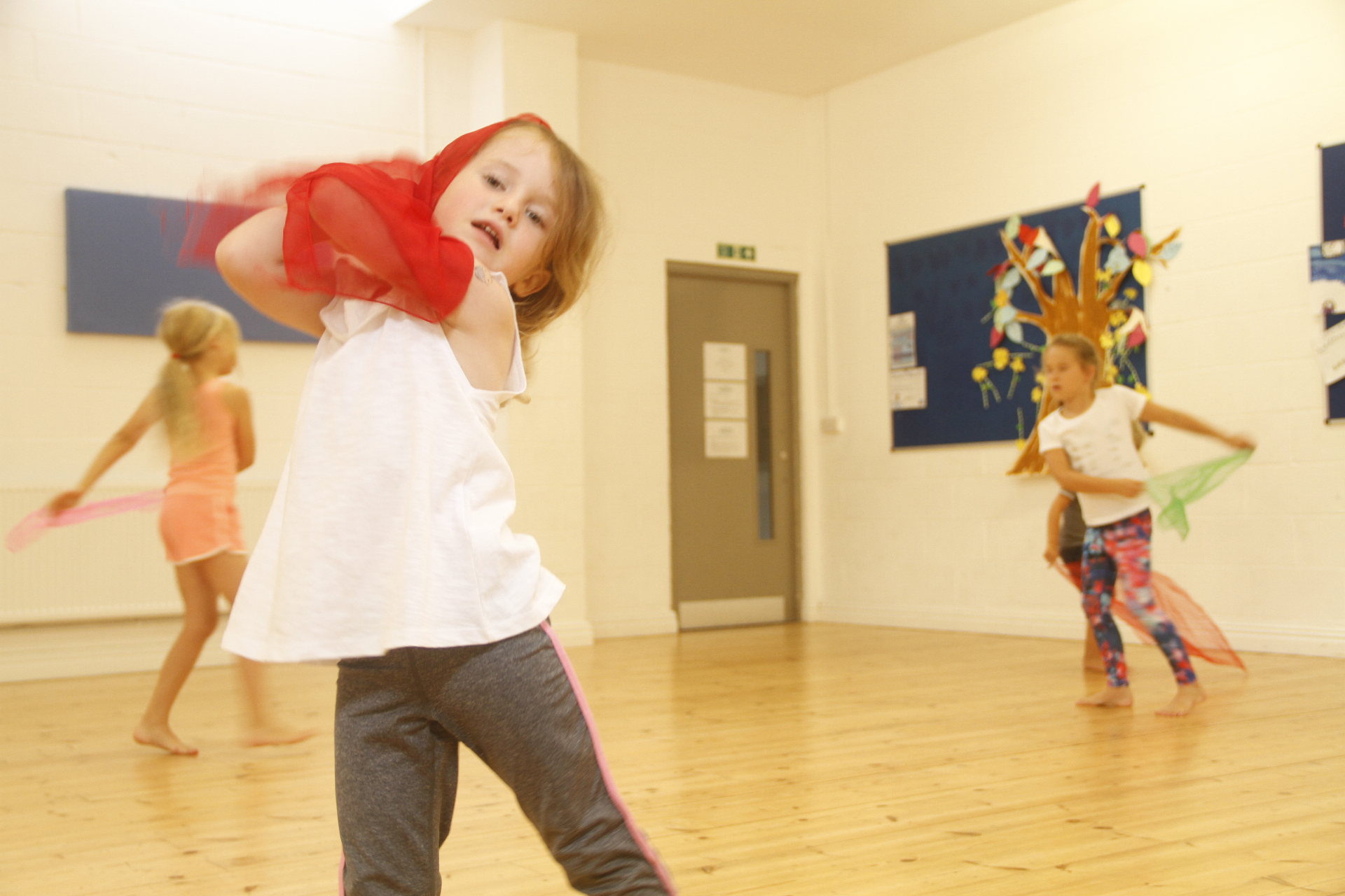 Children dancing with colourful sheer scarves in a school hall